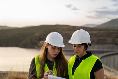 İki kadın mühendis, baraj inşaatının planlarını gözden geçiriyorlar.