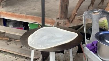 Güneydoğu Asyalı sokak satıcısı fırın tepsisine dilimlenmiş muz ekleyip katlıyor.