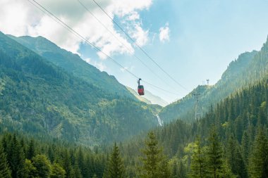 Romanya Karpat Dağları 'nın transfagarasan bölgesindeki pitoresk bir vadiden turistleri taşıyan kırmızı teleferik.