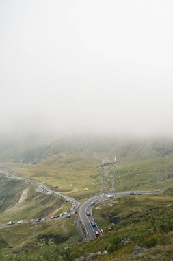 Romanya 'nın dolambaçlı transfagarasan dağ yolunda trafik sıkışıklığı yoğun siste kayboluyor.