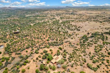 Geniş bir çöl arazisi, uzak dağlar ve yeşillik alanlarına karşı kurulur. Sahne, parlak bir gökyüzünün altında doğal güzellikleri yansıtan sakin bir atmosfer yakalıyor..