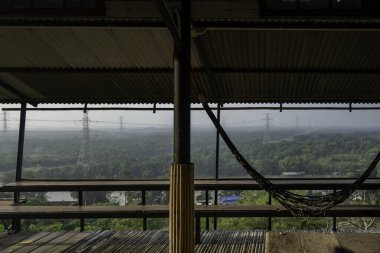 Sıcak, ahşap bir güvertede sandalyeler ve masa bulunur. Sabahları dağların nefes kesici manzarası ve zengin bitki örtüsü için huzurlu bir yer sunar.