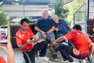 Bangkok, Tayland - 25 Aralık 2024: Turistler canlı bir öğleden sonra etkinliği sırasında Tayland 'daki bir vahşi yaşam sığınağında yılanlarla etkileşime girerler. Yüksek kalite fotoğraf