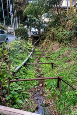 Akıntı, yemyeşil ve kanalizasyon için metal destekli bir yerleşim bölgesinin yanında akıyor. Yüksek kalite fotoğraf