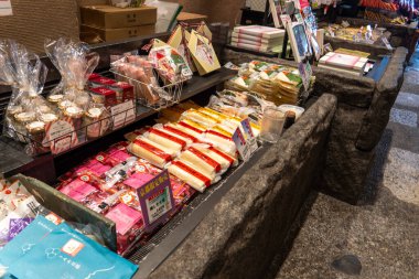 Kyoto, Japonya - 27 Aralık 2024: Kyoto pazarında yerel mutfak kültürünü ön plana çıkaran geleneksel Japon aperatifleri ve tatlılarının canlı gösterimi. Yüksek kalite fotoğraf