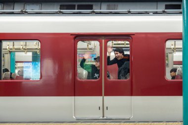 Kyoto, Japonya - 27 Aralık 2024: Gezginler, hareketli bir Japon istasyonundan hareketli bir öğleden sonra ayrılırken el sallıyorlar. Yüksek kalite fotoğraf