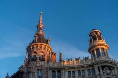 Tepesinde belirgin bir kule bulunan büyük ve etkileyici bir bina, majestelerini yükselten açık mavi bir gökyüzüne karşı kurulmuş.
