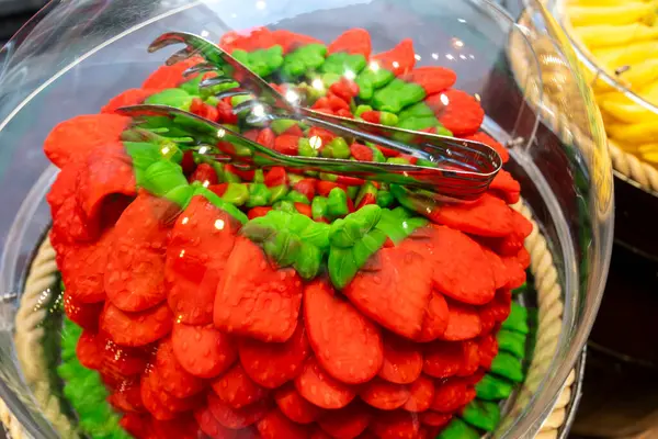 A delicious red and green cake adorned with colorful tongs placed right on top of it for a unique decorative touch