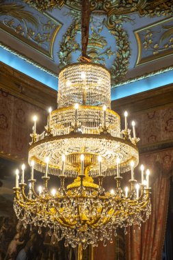 Zarafetiyle gözleri çeken güzel tasarlanmış bir odanın tavanında büyük, süslü bir avize asılıdır.