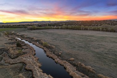 Gün batımında nefes kesen bir nehri görüntüleyen bir hava manzarası. Arka planda güzel bir şekilde silueti olan muhteşem dağlar.