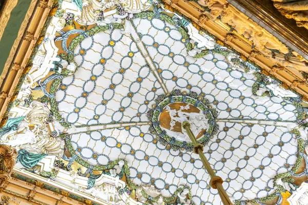 Bu, süslenmiş bir tavanın detaylı bir yakın görüntüsü. Tam üzerine monte edilmiş güzel tasarlanmış bir saat ihtişamını gözler önüne seriyor.