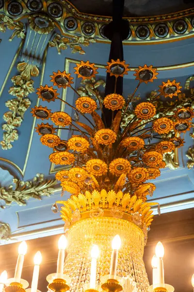 Canlı sarı çiçekler ve zarif mumlarla süslenmiş güzel bir avize tavandan zarif bir şekilde sarkıyor, ılık bir parıltı yayıyor.