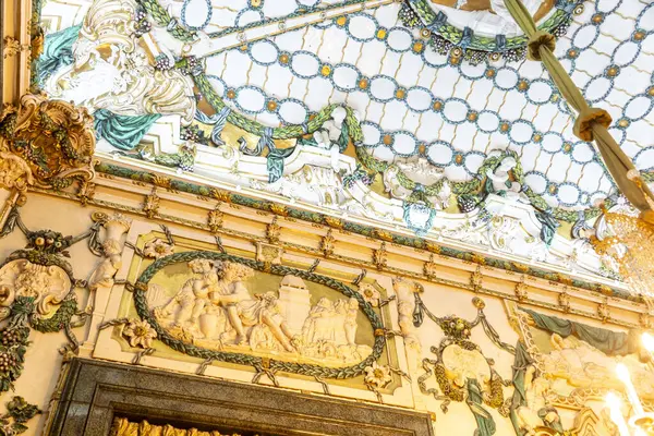 Yüzeyinde estetik cazibe için sayısız karmaşık dekorasyon ve süslemelerle süslenmiş bir tavanı olan bir oda.