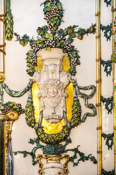 Bu, duvarın içine yerleştirilmiş güzel işlenmiş bir heykelin detaylı bir yakın çekimi. Çiçekler ve üzümlerin karmaşık tasarımları var.