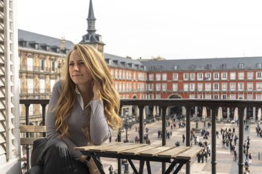 Bir kadın, aşağıdaki kalabalık bir şehre tepeden bakan balkondaki bir masada rahatça oturabilir.