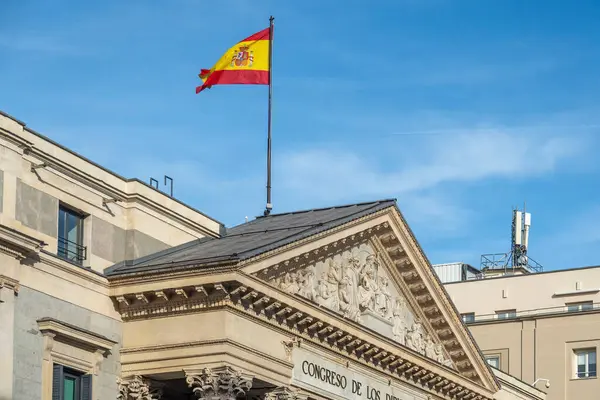 Canlı bir İspanyol bayrağı, önde gelen bir binanın tepesinde gururla dalgalanıyor ve ulusal kimlikle ilgili güçlü bir açıklama yapıyor.