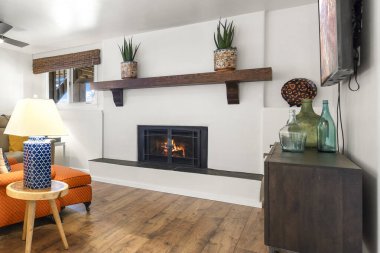 Eğlence ve rahatlama için düz ekran televizyonun yanında sıcak bir şömine bulunan rahat bir oturma odası.