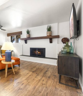 Eğlence ve rahatlama için düz ekran televizyonun yanında sıcak bir şömine bulunan rahat bir oturma odası.