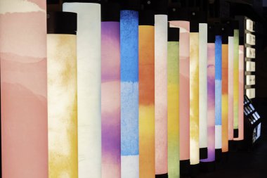 Günbatımında modern bir sergi alanında renkli desenler gösteren parlak sütunlar dizisi. Yüksek kalite fotoğraf