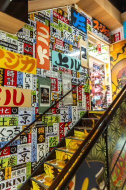 Kyoto, Japonya - 27 Aralık 2024: Canlı kentsel alanda kültürel ifadelerle dolu renkli işaretlerle süslenmiş canlı merdiven. Yüksek kalite fotoğraf