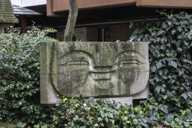 Yeşilliklerin arasına yerleştirilmiş taş heykel Tokyo 'nun sakin bahçesinde benzersiz sanatsal ifadeler sergiliyor. Yüksek kalite fotoğraf
