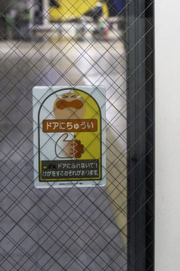 Tokyo, Japonya - 3 Ocak 2025: Yoğun bir Japon kentsel ortamında bir kapıda emsalsiz tasarım unsurları gösteren güvenlik önlemleri bildirimi. Yüksek kalite fotoğraf