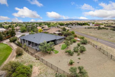 Bu, arka planda manzaralı golf sahası olan ve çitlerle çevrili büyüleyici bir evi gösteren hava manzarası.