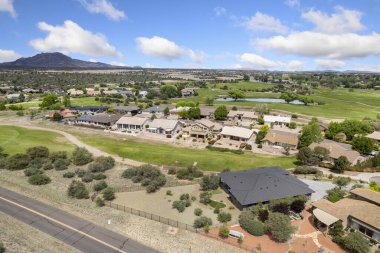 Bu resim, yakınlardaki bir dizi ev ve güzel manzaralı golf sahalarıyla dolu bir yerleşim bölgesinin havadan görüntüsünü sergiliyor.