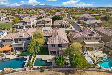 Geniş bir hava manzarası, eğlence için geniş bir yüzme havuzu ve sayısız evle dolu canlı bir yerleşim alanı gösteriyor.