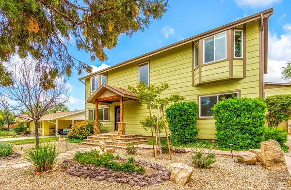 Geniş, büyük sarı bir ev. Önünde çok sayıda pencere ve yemyeşil çalılar var.