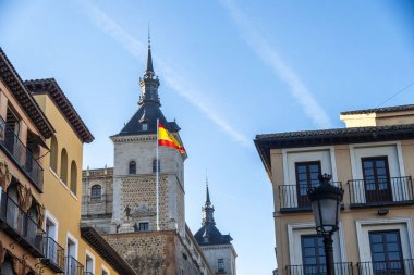 Parlak bir İspanyol bayrağı açık mavi gökyüzüne karşı zarif bir şekilde sallanıyor, güzel bir renk ve sembol sahnesi yaratıyor.