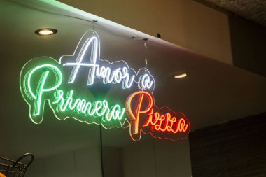 Primavera Pizza yazan parlak neon bir tabela duvarda güzel asılı, kolayca göze çarpıyor ve dikkat çekiyor.