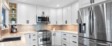 Zarif beyaz dolaplar ve parlak paslanmaz çelik aletlerle donatılmış modern bir mutfak şık ve işlevsel bir mutfak alanı yaratıyor.