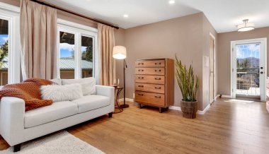 Hoş bir ahşap şifoniyerle tamamlanmış şık beyaz bir kanepenin yer aldığı davetkar bir oturma odası.