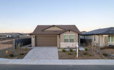 Bu resim, huzurlu bir yerleşim alanına yerleştirilmiş, geniş bir garajı olan büyüleyici bir evin hava görüntüsünü sergiliyor.