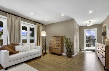 Rahat bir kanepe, şık bir sehpa, bir sandalye ve yerde sıcak bir halı olan rahat ve davetkar bir oturma odası.