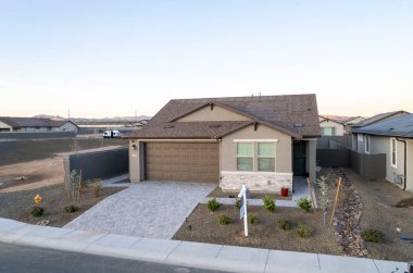 Bu, ağaçlar ve diğer evlerle çevrili güzel gelişmiş bir yerleşim bölgesinde bulunan bir evi gösteren hava görüntüsü.