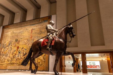 Güçlü bir atın üstünde zarif bir şekilde binen zırhlı bir adamı tasvir eden çarpıcı bir heykel büyüleyici bir sanat eseri olarak hizmet eder.