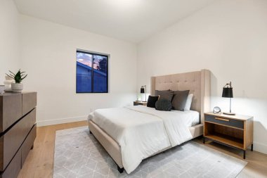 Konforlu bir yatak odası, şık bir komodin, geniş bir şifonyer ve doğal ışık katan güzel bir pencere.