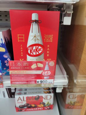 Tokyo, Japonya - 27 Aralık 2024: KitKat çikolatalarıyla dolu bir şişe diğer çeşitli ürün ve ürünlerle birlikte rafın üzerinde yer alıyor