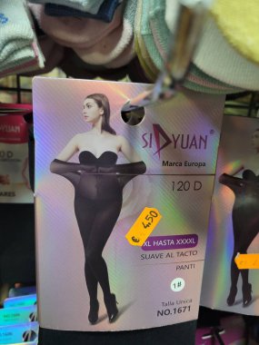 Seville, İspanya - 3 Mart 2024: Bir kadın, çeşitli moda tasarımlarını sergileyen renkli ve şık taytlarla dolu bir kutunun içinde güvenle duruyor