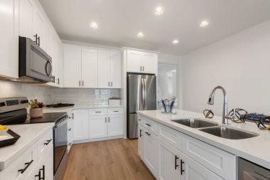 Zarif beyaz dolapları ve modern paslanmaz çelik aletleri olan şık ve işlevsel bir yemek alanı olan iyi tasarlanmış bir mutfak.