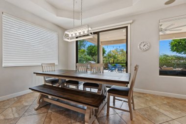 Konukların oturması için bir dizi rahat sandalye ve karşılama tezgahıyla çevrili büyük bir masa içeren rahat bir yemek odası.