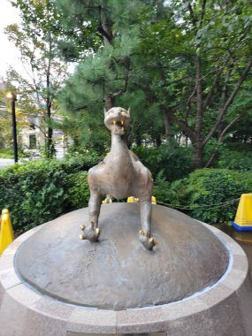 Efsanevi yaratık heykeli güneşli öğleden sonra yemyeşil ve parlak çiçeklerle dolu canlı bir bahçede nöbet tutar. Yüksek kalite fotoğraf