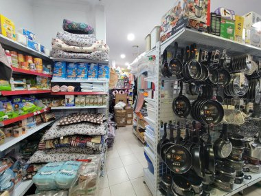 Sayısız rafla dolu bir mağazanın içinde farklı şekil ve boyutlarda tencere ve tavalar var.