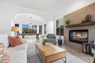 Sıcak bir şöminesi, rahat bir koltuğu, şık bir masası ve rahatlamak için davet edilen sandalyeleri olan rahat bir oturma odası.