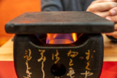 Geleneksel Japon yemek pişirme deneyimi. Masa üstü alevi ve rahat bir yemek yerinde minimalist bir tasarım. Yüksek kalite fotoğraf