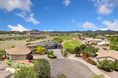 Bu görüntü, ağaçlarla çevrili çeşitli evleri gösteren ilginç ve büyüleyici bir hava manzarası sunuyor.