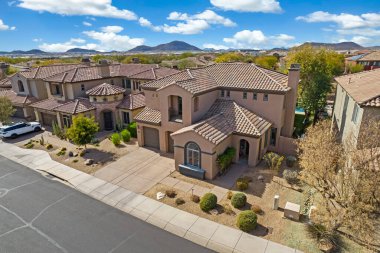 Bu, evlerle ve yeşilliklerle dolu geniş bir yerleşim alanı içinde belirgin bir şekilde yer alan büyük bir evi gösteren bir hava görüntüsü.