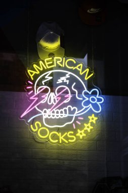 Amerikan çoraplarının reklamında parlak bir neon tabela güzel bir çiçek motifi ile sarmalanmış çarpıcı bir kafatası tasarımı sergiliyor.